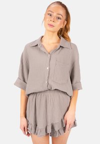 Ensemble deux pièces en coton gris comprenant un haut à boutons avec une poche et des manches retroussées, associé à une jupe à volants pour un look décontracté.