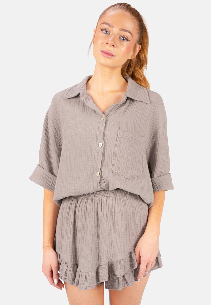 Ensemble deux pièces en coton gris comprenant un haut à boutons avec une poche et des manches retroussées, associé à une jupe à volants pour un look décontracté.