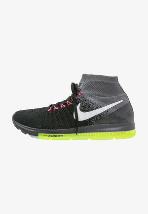 Sneakers Nike Zoom avec un dessus en tricot noir et gris, des lacets roses et une semelle vert vif. Logo Swoosh emblématique en blanc sur le côté.