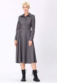 Robe grise à rayures à manches longues avec un col à boutons et une taille ceinturée, associée à des bottes à lacets noires. Tissu lisse et silhouette fluide.