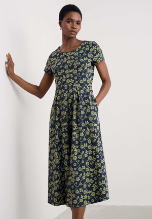 Navy dress with short sleeves, green floral pattern, fitted bodice, flared skirt, and side pockets. Made from lightweight, smooth fabric.