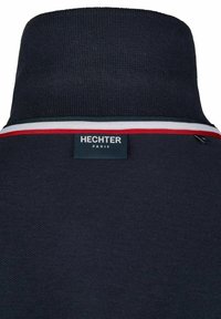 Marineblaues Strickpolo mit einem kontrastierenden gestreiften Akzent in Rot, Weiß und Grün. Auf der Rückseite befindet sich ein Etikett mit der Aufschrift "HECHTER PARIS".