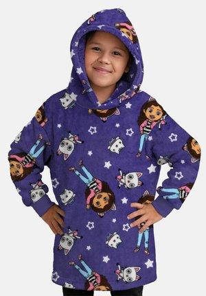 Kind lächelt und trägt einen violetten Fleecepullover mit Kapuze, bedruckt mit Cartoon-Mädchen- und Katzenfiguren sowie weißen Sternen.