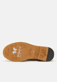 Suela de un zapato en color marrón claro con goma texturizada para agarre, con un logo impreso y la talla. El diseño muestra patrones de desgaste en la superficie.