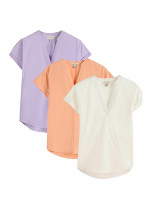 Trois blouses à manches courtes en lavande, pêche et blanc avec col en V et coupe décontractée, disposées en chevauchement sur un fond blanc.