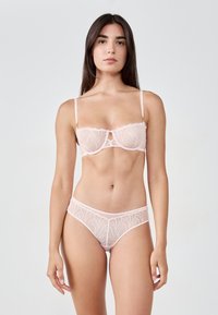 Lace lingerie set in zachtroze, met een bloemenpatroon, verstelbare bandjes en doorschijnende details op zowel de beha als de slip.