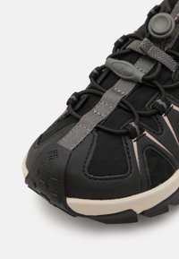 Svarte joggesko laget av stoff og gummi, med grå detaljer, en teksturert tåhette og et bungee-snøresystem for sikker passform.