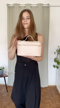 Helles rosa rechteckiges Handtasche mit einem Reißverschluss, das ein gemustertes Design und doppelte Griffe aufweist. Die Tasche besteht aus synthetischem Material.