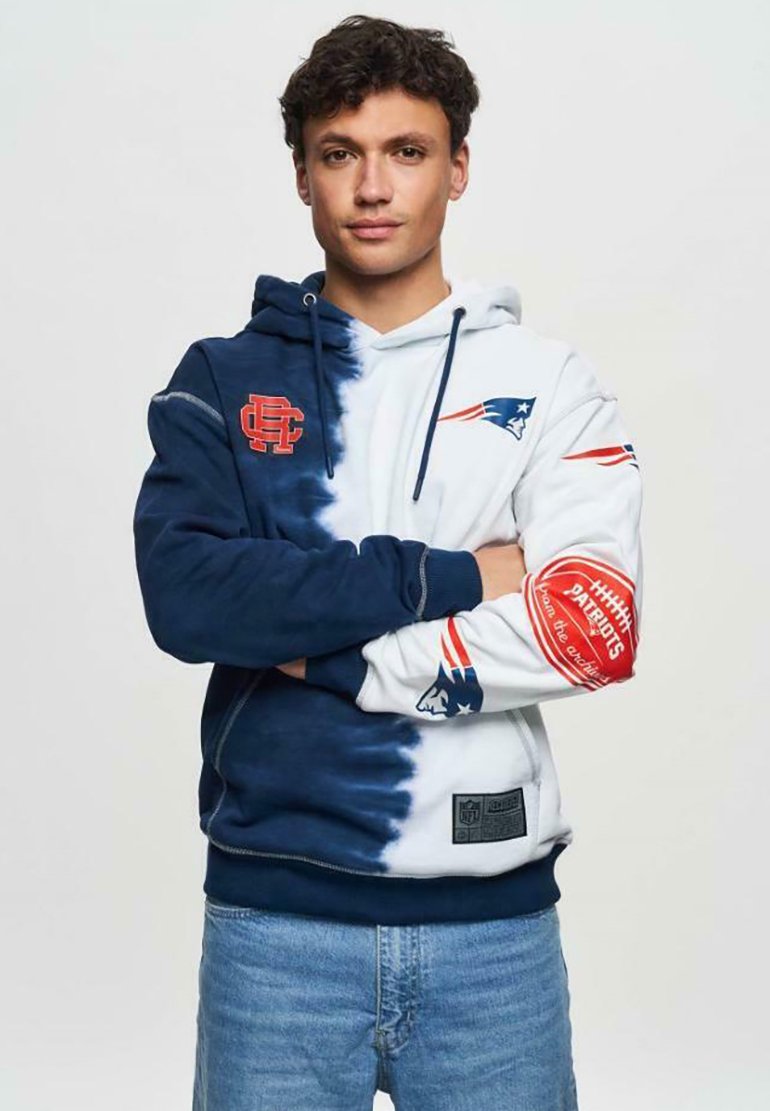 Sweat à capuche présentant un dégradé bleu et blanc, logo des Patriots de la NFL, et accents rouges. Fabriqué en tissu doux, affichant des graphismes aux thèmes sportifs.