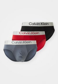 Calvin Klein Herrenunterwäsche in Grau, Rot und Schwarz. Jede bietet einen breiten elastischen Bund mit Logo, glattes Material und eine eng anliegende Passform.