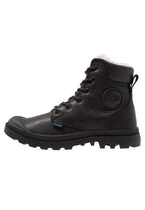 Bottine montante en cuir noir avec col rembourré, fermeture avant à lacets, semelle épaisse crantée et logo rond Palladium sur le côté.