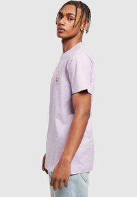 Lilac short-sleeve t-shirt made of cotton, featuring a small multicolored floral design on the chest. Straight cut with a relaxed fit.