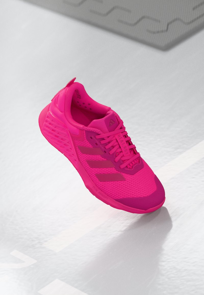 Bright pink athletic shoe with mesh upper, textured lace area, and rubber sole. Features three logo stripes and padded heel for comfort.