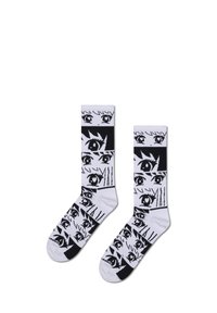 Bílé ponožky s opakujícím se grafickým vzorem černých očí a čar, na kontrastních černých sekcích na manžetách a špičkách.