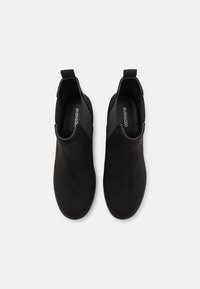 Black ankle boots made of suede, featuring a sleek design, rounded toe, and elastic side panels for easy wear. Textured upper and smooth lining.