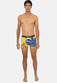 Boxers pour hommes en bleu, jaune et vert avec des motifs tropicaux, dotés d'une taille noire avec le logo "WAXX". Tissu extensible, coupe ajustée.