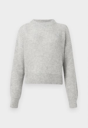 Pull en maille gris clair avec une texture côtelée, coupe courte, col montant et manches longues. Dispose d'un petit logo.