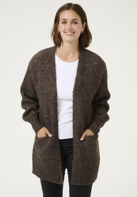 Hnědá pletená cardigan s dlouhými rukávy, otevřeným předním dílem a dvěma předními kapsami. Vyrobeno z texturovaného, měkkého materiálu s volným střihem.