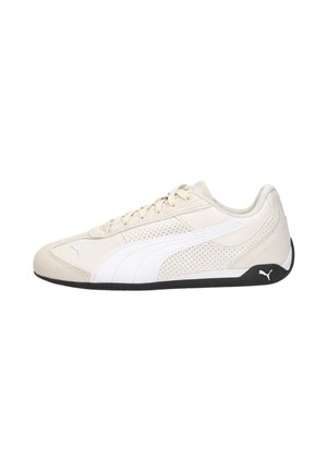Baskets Puma beige clair avec accents de bandes blanches, côtés perforés, fermeture à lacets et semelle noire avec logo Puma au talon.