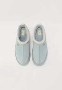 Lichtblauwe suede pantoffels met een zachte, pluizige binnenkant, decoratieve stiksels langs de kraag en een kleine hieltrap voor gemakkelijk aan- en uittrekken.