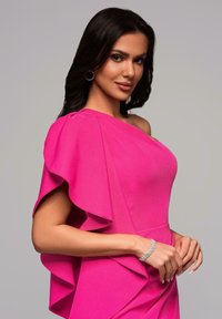 Robe fuchsia à une épaule avec détails de manches à volants, fabriquée en tissu doux. Présente une silhouette élégante et un drapé subtil. Accent de bracelet scintillant.