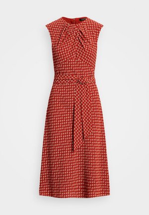 Robe midi rouge sans manches avec motif géométrique blanc, encolure ronde, corsage plissé et ceinture en tissu assorti nouée à la taille.