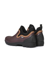 Brune gummist�øvler til anklerne med sorte accenter, der har en tekstureret overflade og et slip-on design. Omfatter et lille logo på siden.