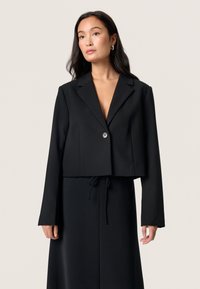 Czarna, krótka marynarka z gładkiego materiału, zapinana na jeden guzik, z klapami, długimi rękawami i dopasowanym krojem.