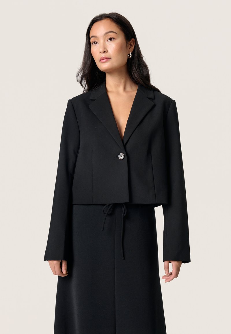 Czarna, krótka marynarka z gładkiego materiału, zapinana na jeden guzik, z klapami, długimi rękawami i dopasowanym krojem.