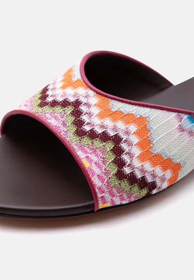 Sandale mule à bout ouvert avec empeigne en tricot zigzag multicolore et bordure bordeaux sur semelle marron foncé.
