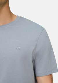 Lys blå kortærmet T-shirt lavet af glat bomuld, med et diskret broderet logo på brystet og en rund halsudskæring.