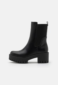 Botas de tobillo negras de cuero suave, con paneles laterales elásticos, un tacón grueso y un acento estampado en la parte trasera.