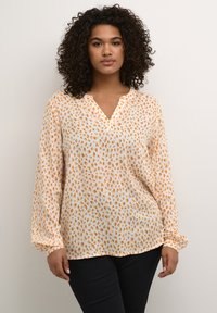 Lightweight, long-sleeve blouse in cream with an orange and brown speckled pattern; V-neck design and slightly loose fit.