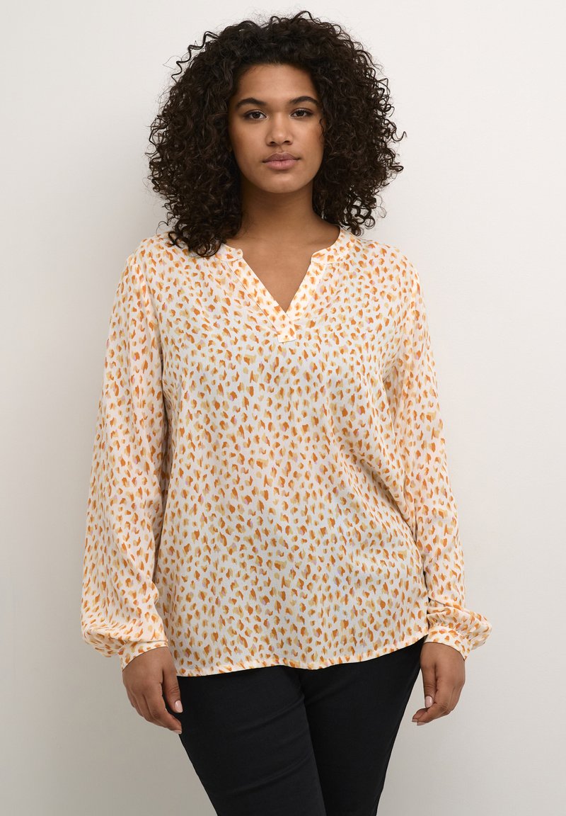 Lightweight, long-sleeve blouse in cream with an orange and brown speckled pattern; V-neck design and slightly loose fit.