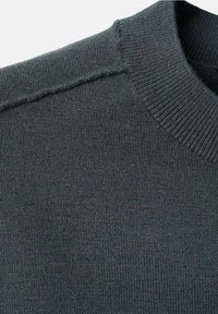 Détail d'un pull en maille gris foncé montrant un col rond côtelé et une couture d'épaule.