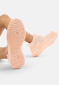 Rosa Sport-Schuhe mit strukturiertem Obermaterial aus Stoff und einer gemusterten Gummisohle. Verfügt über ein glattes, flexibles Design mit einer Zuglasche am hinteren Teil.