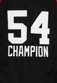 Črn športni dres iz mrežaste tkanine z izrazitim belim besedilom "54" nad "ŠAMPION" v jasni, blokovni pisavi z rdečimi poudarki.