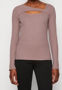 Långärmad ribbat topp i mauve med asymmetrisk halsringning och utskärning. Mjuk tygkvalitet med en figurnära passform, lämplig för lager-på-lager.