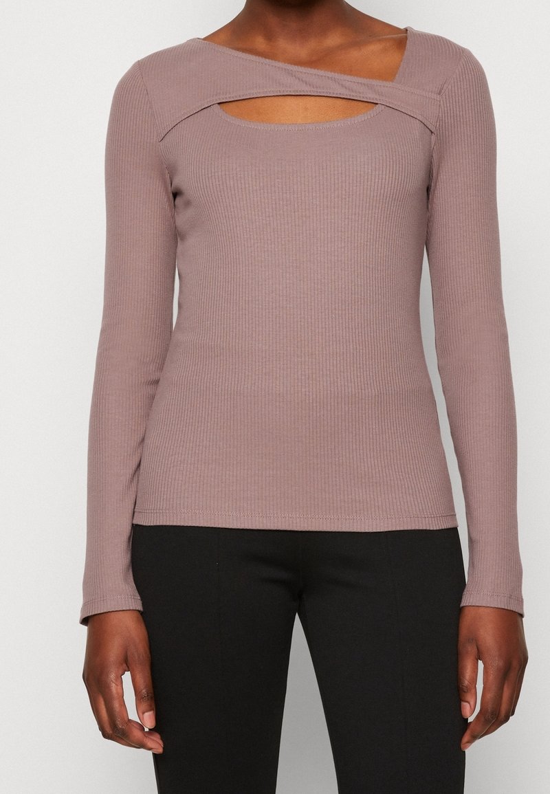 Långärmad ribbat topp i mauve med asymmetrisk halsringning och utskärning. Mjuk tygkvalitet med en figurnära passform, lämplig för lager-på-lager.