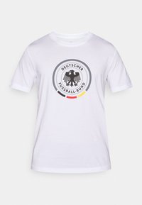 Fehér pamut póló kör alakú logóval, amelyen egy fekete sas látható és a "Deutscher Fußball-Bund" felirat szerepel, a kiemelő színek sárga, piros és fekete.