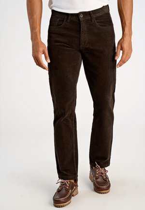 Pantaloni in velluto a coste marroni con una vestibilità slim, dotati di chiusura a bottone tradizionale e cinque tasche, abbinati a scarpe mocassino in pelle marrone.