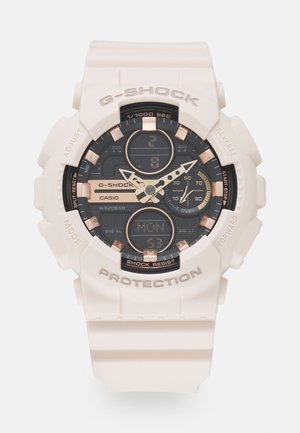 G-SHOCK watch with a white resin band, black and gold dial, analog and digital displays, and protective bezel. Features include a shock resistance and a calendar.