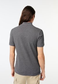 Camisa polo gris de manga corta, con tejido texturizado y cuello. El diseño presenta un corte relajado y un dobladillo recto.