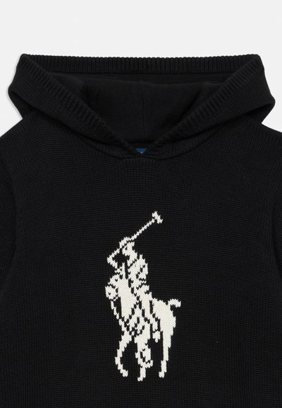Melnā adīta kapuce ar izteiktu baltu polo spēlētāja logotipu, teksturēta auduma un ribotā apkakle.