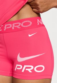 Ružové športové šortky s textúrovaným pásom a nápisom "PRO" v bielom písme, a bielym logom Nike swoosh na boku.