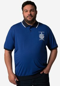 Modrá polo košile s černým límečkem a manžetami. Na hrudi má námořnický vzor s bílou výšivkou a knoflíky.