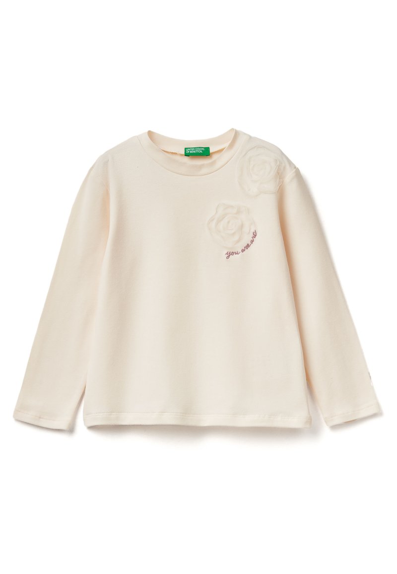 Krémové tričko s dlouhým rukávem z měkkého materiálu. Obsahuje dvě strukturované látkové aplikace ve tvaru růže a vyšívaný text "jseš skvělý" na hrudi.