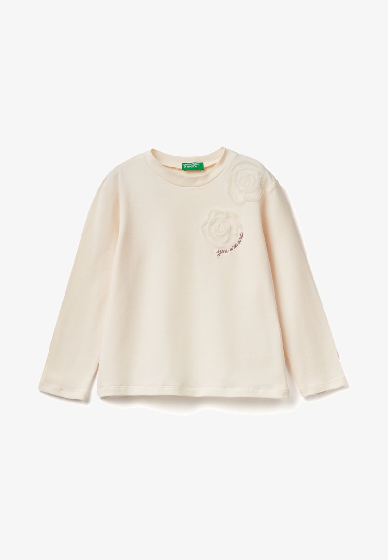 Krémové tričko s dlouhým rukávem z měkkého materiálu. Obsahuje dvě strukturované látkové aplikace ve tvaru růže a vyšívaný text "jseš skvělý" na hrudi.