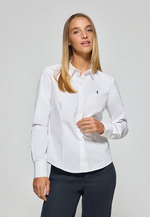 Camicia bianca con bottoni, realizzata in cotone, con una vestibilità slim. Presenta un colletto classico e un piccolo logo ricamato sul lato sinistro del petto.