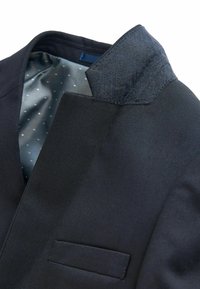 Giacca nera con colletto testurizzato, fodera liscia con un motivo a pois e una tasca sul petto.